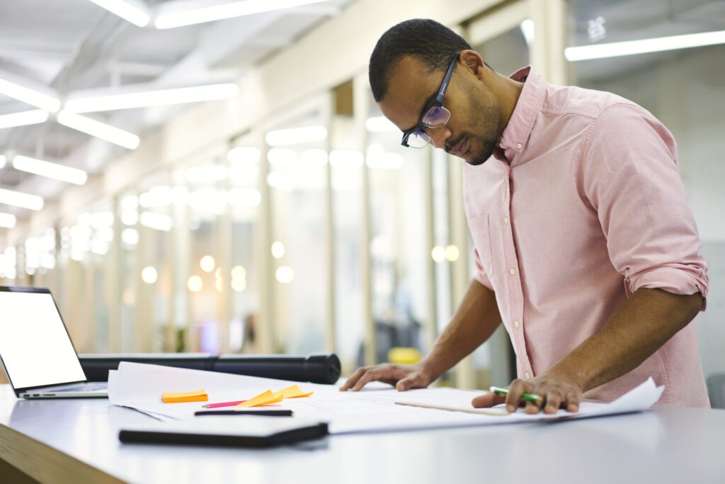 Well-dressed mindful male architect in trendy glasses verifying data information from online map